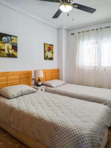 two beds in a bedroom with a ceiling fan at Apartment Viñamar 6 La Mata in La Mata
