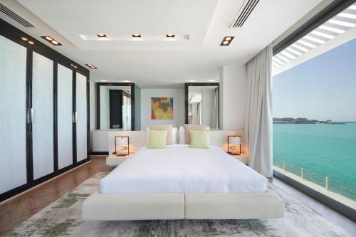 a bedroom with a large white bed and large windows at Nurai Island’s Overwater Paradise : Luxury Retreat in Abu Dhabi