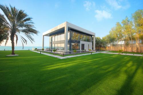 a house with a large lawn in front of it at Nurai Island’s Overwater Paradise : Luxury Retreat in Abu Dhabi