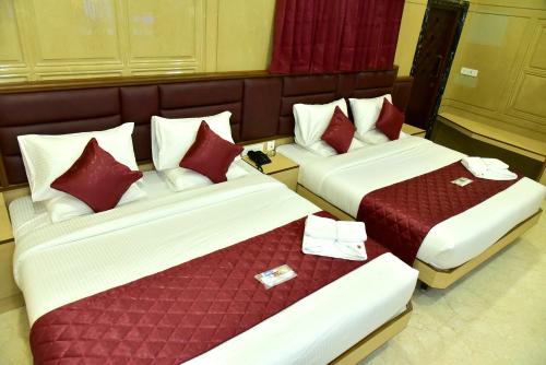 two beds in a hotel room with red pillows at Majestic Hotel in Madurai