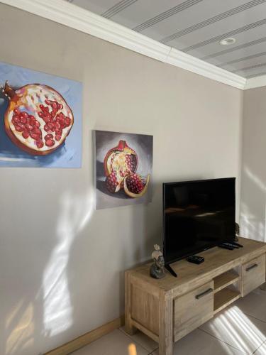a living room with a television and a pizza on the wall at Aloes Lodge in Leribe