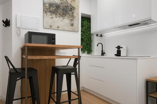 eine Küche mit zwei Hockern und einem Tisch mit einer Mikrowelle in der Unterkunft Tourist House Francos in Sevilla