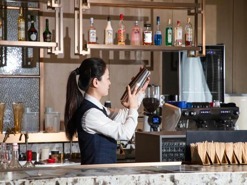 a woman standing behind a bar holding a book at Kunshan Kasion Hotel in Kunshan