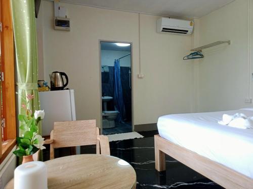 a bedroom with a bed and a table and a bathroom at Kiangna resort Chiang Rai in Ban Pa O (1)