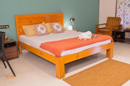 a bedroom with a wooden bed with an orange blanket at Euphoria Farmstay Pure Veg Khopoli in Āmbavna