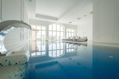 a room with a swimming pool with a table and chairs at KADORR Hotel Resort & Spa in Odesa