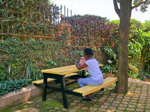a woman sitting at a picnic table in a garden at Viola Hotel Limited in Mbale