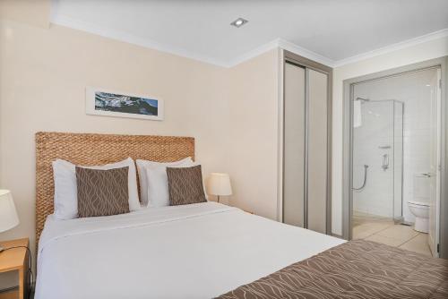 a bedroom with a large bed and a bathroom at Crow's Nest Apartments in Whitianga