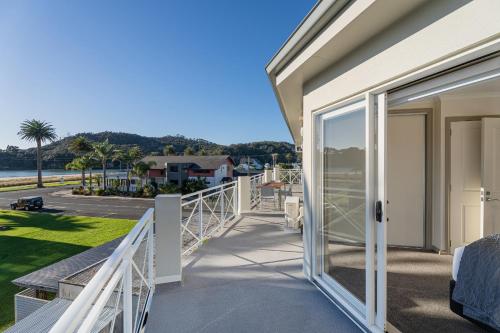 a balcony with sliding glass doors looking out at the water at Crow's Nest Apartments in Whitianga