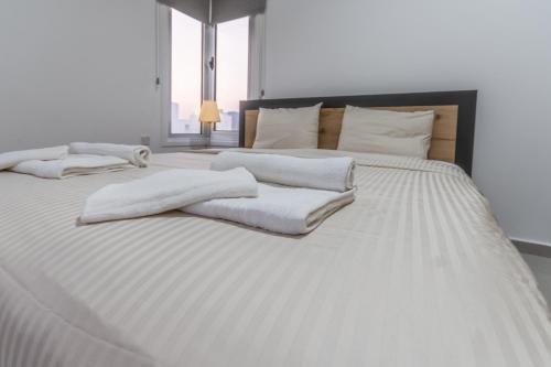 a white bed with white blankets and pillows on it at Black Swan Villa in Pervolia