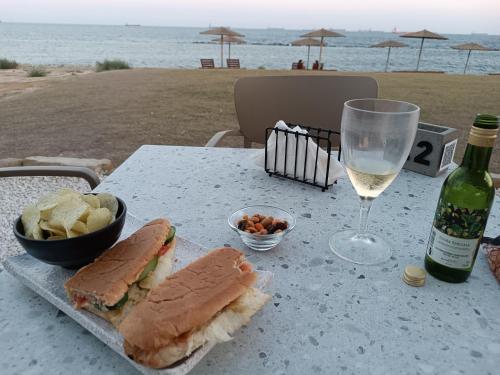 a table with a sandwich and a glass of wine and chips at Danitsea villa with privat pool in Psematismenos
