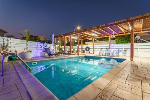 a swimming pool with a pergola next to a house at Black Swan Villa in Pervolia