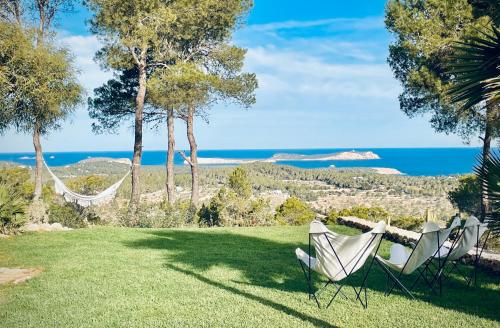two chairs and a hammock on a lawn with the ocean at Blue Hill House Ibiza 360-degree Exclusiveness in San Jose