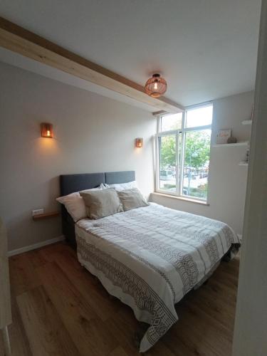a bedroom with a large bed with a window at Mediterranean apartment with home theater in Bodegraven