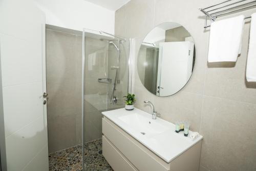 a white bathroom with a sink and a mirror at HaBaitBe Matityahu By Domus in Beer Sheva