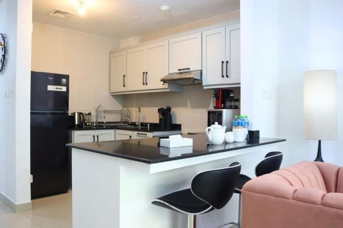 a kitchen with white cabinets and a black refrigerator at Modern Haven 1BR - Peaceful & Stylish Escape in Abu Dhabi