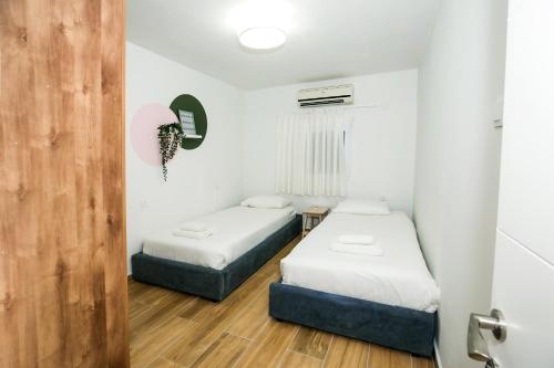 two beds in a room with white walls and wooden floors at HaBaitBe Matityahu By Domus in Beer Sheva