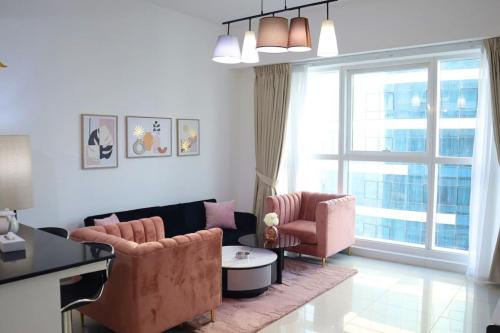 a living room with two chairs and a large window at Modern Haven 1BR - Peaceful & Stylish Escape in Abu Dhabi