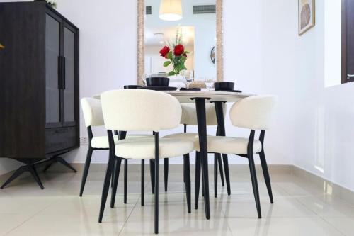 a dining room table with white chairs and a television at Modern Haven 1BR - Peaceful & Stylish Escape in Abu Dhabi