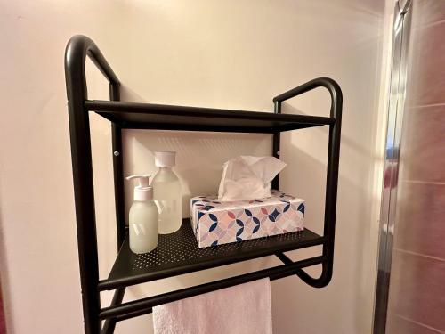 a black shelf with a bottle and a box of tissues at Le Chat De Lamartine - Clim Parking in Saint-Pierre-dʼAlbigny