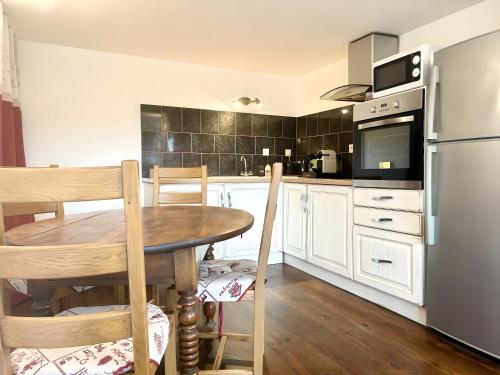 a kitchen with a wooden table and a refrigerator at Le Chat De Lamartine - Clim Parking in Saint-Pierre-dʼAlbigny