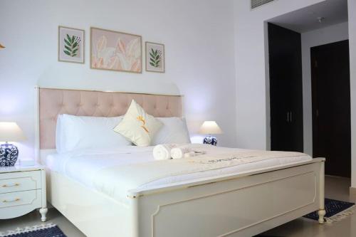 a bedroom with a large white bed with a pink headboard at Modern Haven 1BR - Peaceful & Stylish Escape in Abu Dhabi