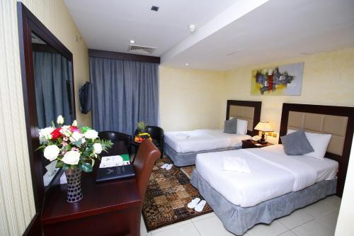 a hotel room with two beds and a table with flowers at Royal Falcon Hotel in Dubai
