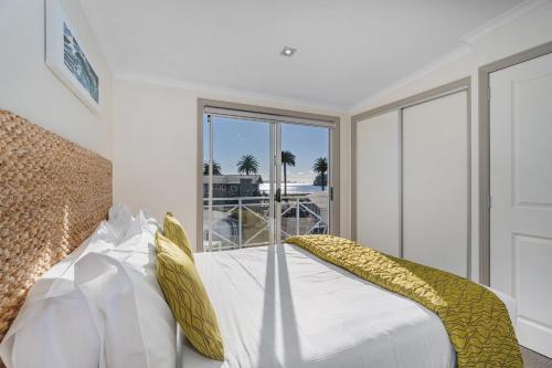 a bedroom with a bed with white sheets and yellow pillows at Crow's Nest Apartments in Whitianga