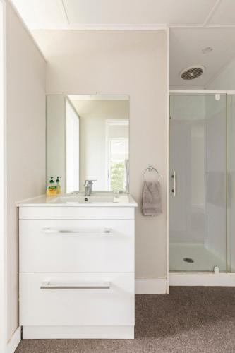 a white bathroom with a sink and a shower at Home away from home 4 bedroom 2 bathrooms in Upper Hutt