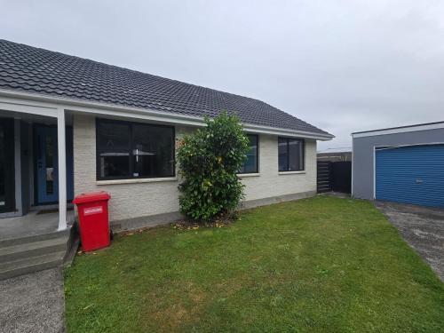 a house with a red trash can in the yard at Home away from home 4 bedroom 2 bathrooms in Upper Hutt