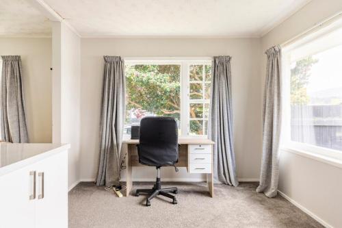 an office with a desk and a chair in front of a window at Home away from home 4 bedroom 2 bathrooms in Upper Hutt