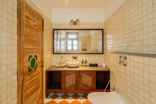 a bathroom with a sink and a mirror and a toilet at Tranquil Trails- Amayah Neer 3-BHK Villa Near Assagao in Assagao