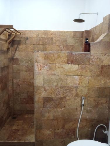 a bathroom with a shower with a stone wall at Dili Gili in Gili Trawangan