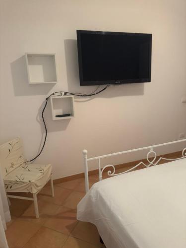 a flat screen tv hanging on a white wall at Villetta giardino, piscina, mare in Campofelice di Roccella