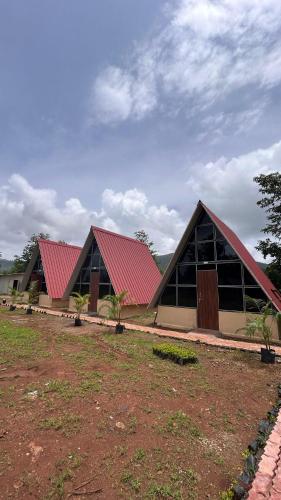 a building with a red roof and two buildings at Huts And Hunters Resort Saputara in Saputara