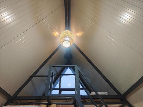a light in a barn ceiling with a window at Huts And Hunters Resort Saputara in Saputara