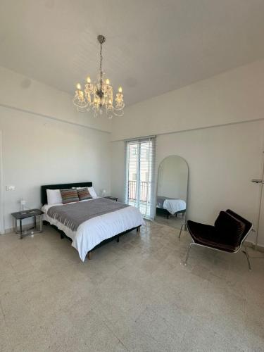 Un dormitorio con una cama, una lámpara de araña y una silla. en Maison Lumiere 2-BD, en Beirut