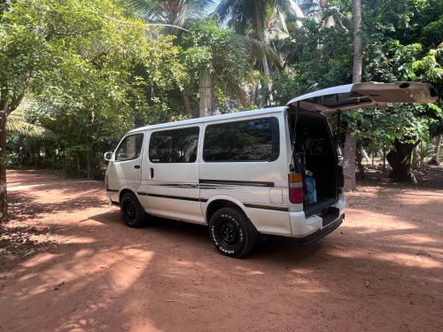 a white van parked on a dirt road with its doors open at Vaakai Home Stay in Adampan
