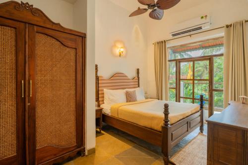 a bedroom with a large bed and a window at Amayah Vayu 6-BHK Indo-Portuguese Escape With Common Pool in Assagao