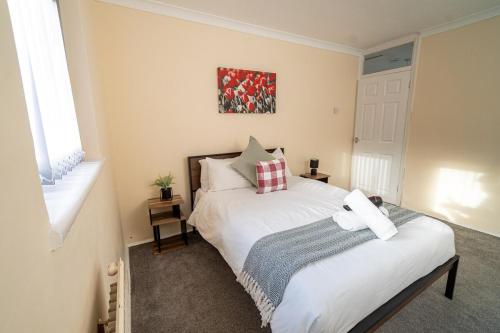 a bedroom with a white bed and a window at Comfortable 4-Bed Home with Free Parking in Swansea