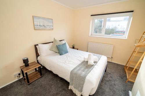 a bedroom with a bed and a window at Comfortable 4-Bed Home with Free Parking in Swansea