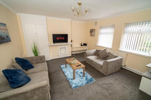 a living room with two couches and a tv at Comfortable 4-Bed Home with Free Parking in Swansea