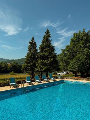 a swimming pool with blue lounge chairs and trees at Heritage Home Ustikolina in Foča