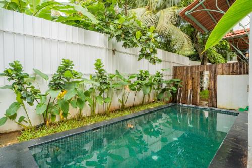 a swimming pool in front of a fence with plants at Luxury 9-BHK Villa with Indo-Portuguese Charm & Pool in Assagao