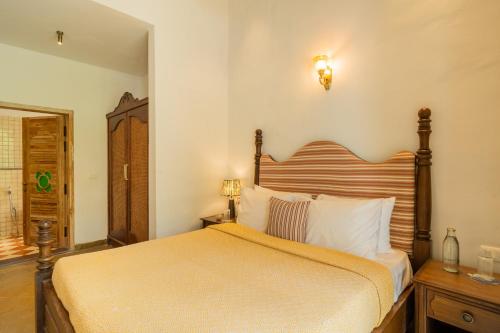 a bedroom with a large bed with a wooden headboard at Luxury 9-BHK Villa with Indo-Portuguese Charm & Pool in Assagao