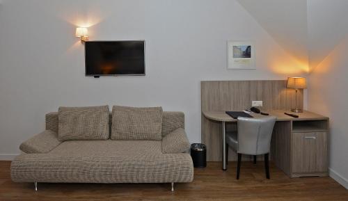 a living room with a couch and a desk with a television at Best Western City Hotel Woerden in Woerden