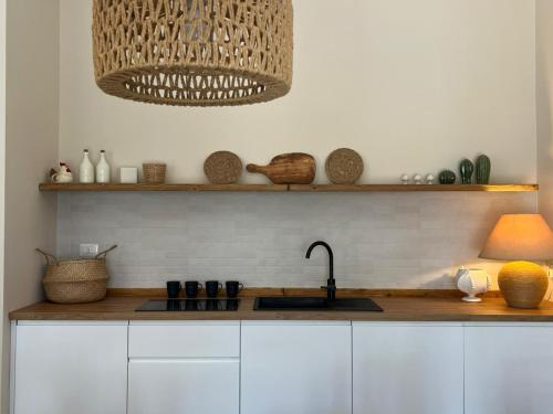 a kitchen with white cabinets and a sink and shelf at Villa Luisa Guest House in Scanzano