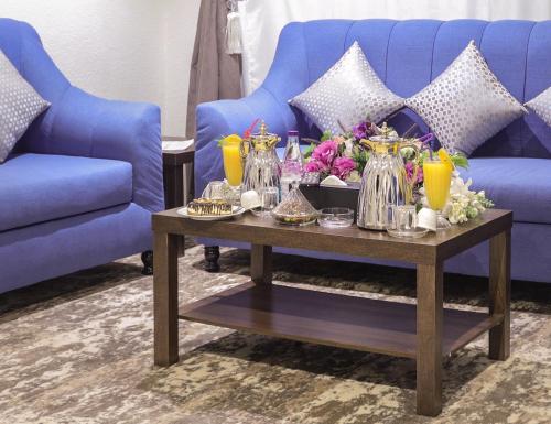 a living room with a blue couch and a coffee table at فندق إطلالة الحديقة in Tabuk