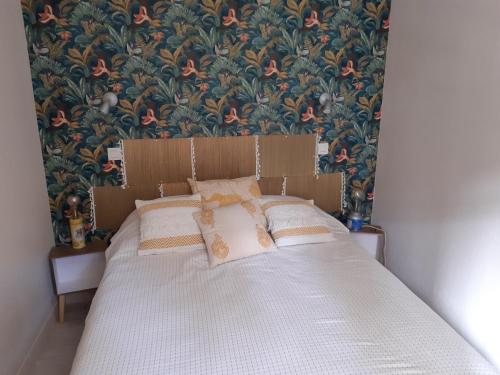 a bed in a bedroom with a floral wallpaper at Appartement T2 avec piscine privée et chauffée in Lacanau