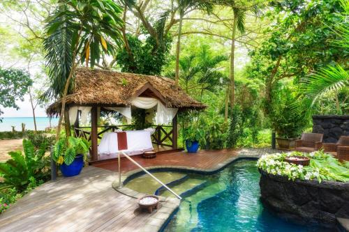 a resort with a swimming pool and a hut at Sheraton Samoa Beach Resort in Mulifanua